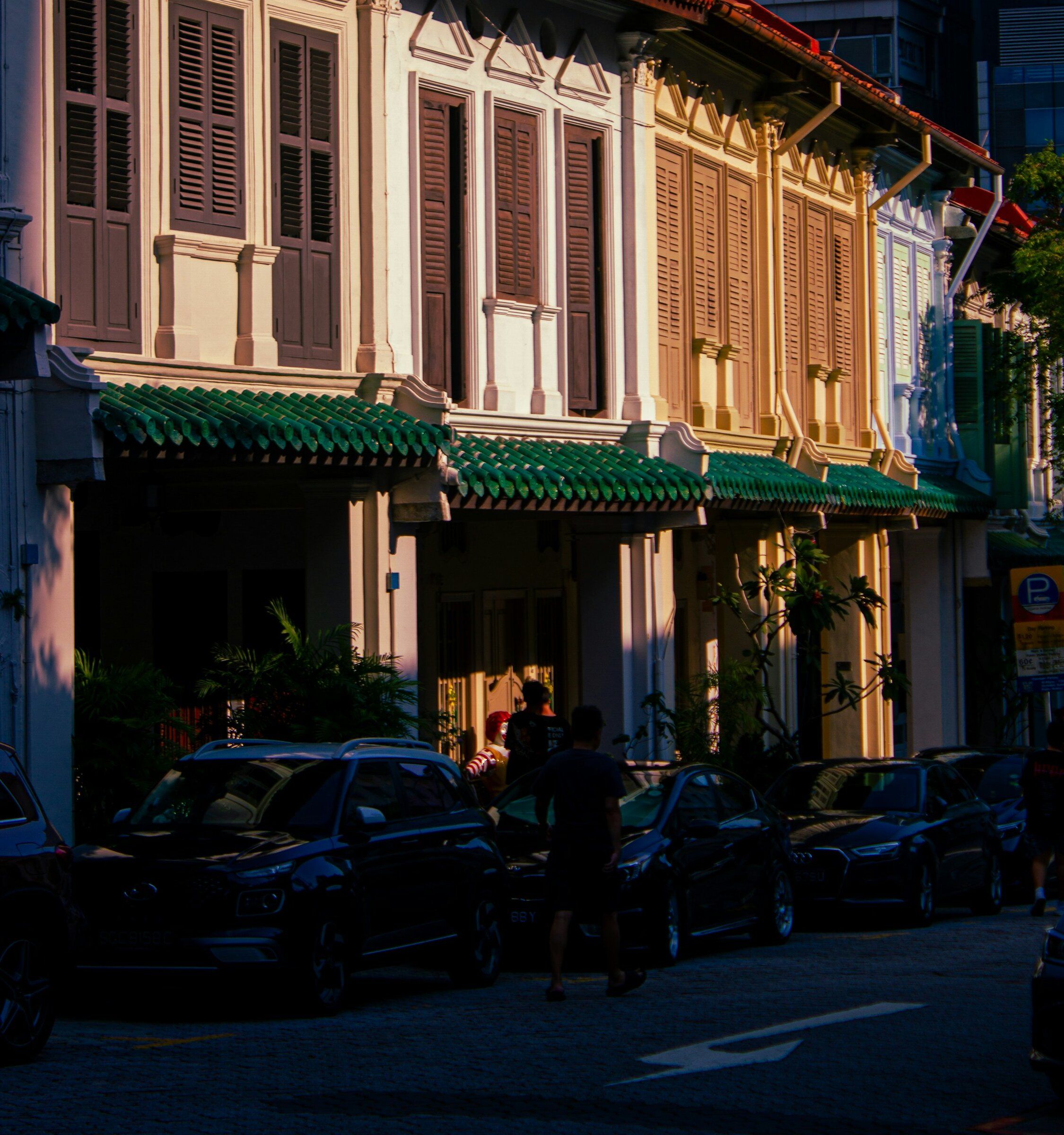 Shophouse facades with timber shutters and green glazed roof tiles in evening light, Singapore